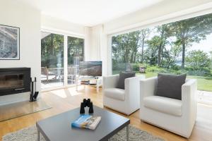 a living room with white furniture and large windows at Hohrott 17 Villa Bellevue I in Heikendorf