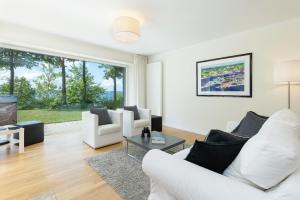 a living room with white furniture and a large window at Hohrott 17 Villa Bellevue I in Heikendorf