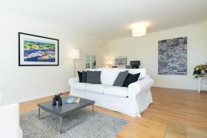 a white living room with a white couch and a table at Hohrott 17 Villa Bellevue I in Heikendorf