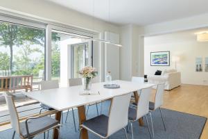a dining room with a white table and chairs at Hohrott 17 Villa Bellevue I in Heikendorf +40 photos