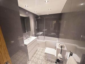 a bathroom with a sink and a toilet and a tub at Maple Lodge Cottage in Blagdon