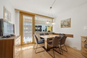 a dining room with a table and chairs and a tv at Kaprun Apartments in Kaprun