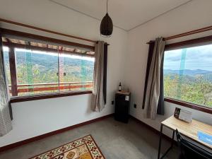a room with two windows and a desk and a table at Vila Literária Tabuleiro in Conceição do Mato Dentro