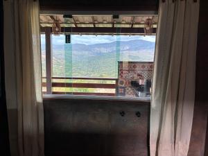 a window with a view of a mountain view at Vila Literária Tabuleiro in Conceição do Mato Dentro +2 photos