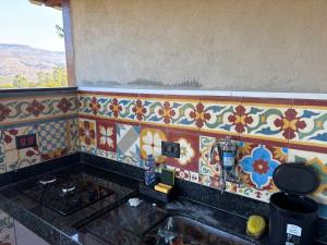 a kitchen counter with colorful tile on the wall at Vila Literária Tabuleiro in Conceição do Mato Dentro