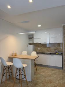 a kitchen with white cabinets and a table and stools at Sarajevo Center Point in Sarajevo