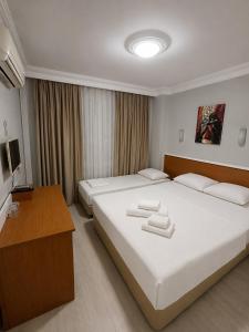 a hotel room with two beds and a desk at Butik İsabel Otel in Kemer