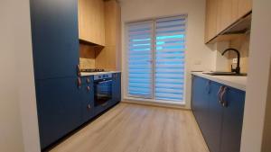 a kitchen with blue cabinets and a large window at 85th Pool View 2 Rooms Apartament in Popeşti-Leordeni