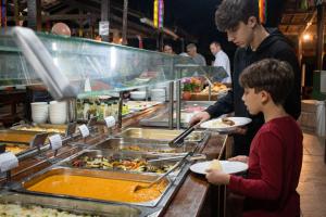 a man and a boy getting food from a buffet at Apt Flat 210 Condomínio Pedra do Rodeadouro in Bonito