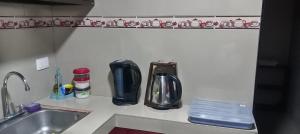 a kitchen counter with two coffeemakers and a sink at Apartamentos Caimán Tortuguero in Tortuguero