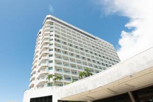 a tall white building with palm trees in front of it at Royal Twins Palace Hotel in Pattaya