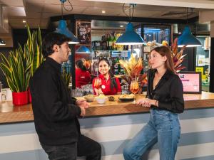 a man and a woman standing at a bar at Ibis Milano Centro in Milan