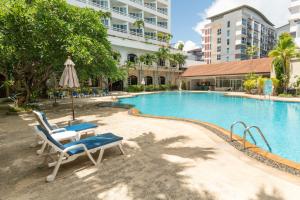 a swimming pool with chairs and a table and an umbrella at Royal Twins Palace Hotel in Pattaya