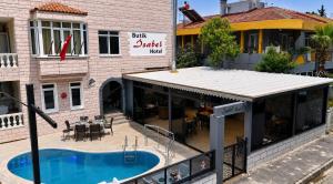 a restaurant with a swimming pool in front of a building at Butik İsabel Otel in Kemer