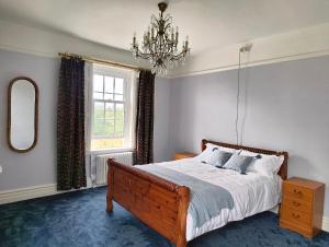 a bedroom with a large bed and a chandelier at Bardon Hill Manor in Coalville