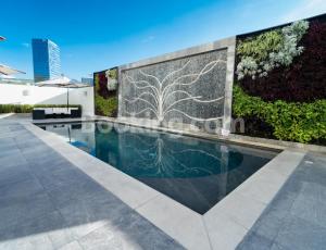 a swimming pool in front of a wall with a garden at HS HOTSSON Hotel Queretaro in Querétaro