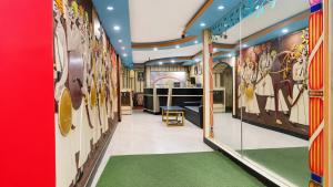 a hallway with green carpeting and paintings on the walls at new crown hotel in Indore