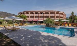 a resort with a swimming pool with chairs and umbrellas at Stella-Bianca in Sagone