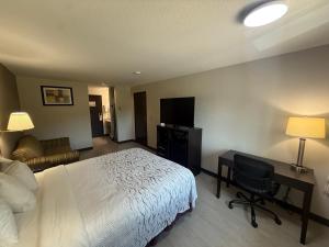a hotel room with a bed and a desk and a television at Red Roof PLUS Centralia in Centralia +23 photos