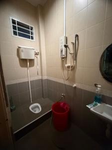 a bathroom with a toilet and a red bucket at D Aida Homestay Bukit Katil in Kampong Bukit Katil +10 photos