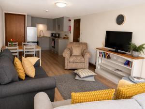 a living room with a couch and a tv and a kitchen at Howgills Apartments in Sedbergh