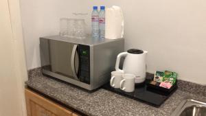 a microwave on a counter with mugs and water bottles at Afrilodge Liberia in Monrovia