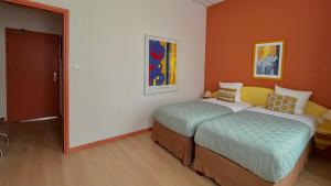 two beds in a room with orange walls at Logis-Hôtel des Oliviers in Thionville