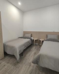 two beds in a white room with wooden floors at AlvaLoft Barreiro in Barreiro