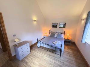 a bedroom with a bed and a dresser and two lamps at Willoughby Lodges in Blagdon