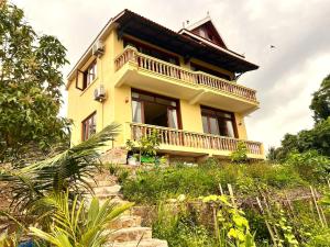 a yellow house with a balcony on a hill at Family-friendly accomodation with sea view in Kaôh Kon