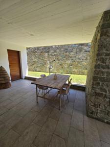 Ein Holztisch und Stühle in einem Raum mit einer Steinwand in der Unterkunft Maison Biula in Cerise