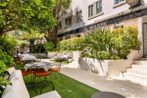a patio with tables and chairs in front of a building at Hotel Molière in Cannes