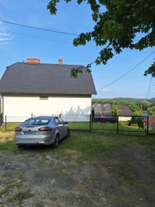 a car parked in front of a white house at Apartament Alicja in Chmielno