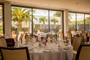 a dining room with tables and chairs and windows at Antillia Hotel in Ponta Delgada