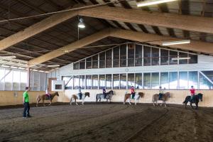 un grupo de personas montando caballos en un edificio en Hotel Reitzentrum Hausruckhof en Ampflwang im Hausruckwald