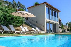 a pool with chairs and an umbrella next to a house at aMaRe Country House in Caminha