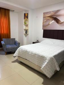 a bedroom with a bed and a blue chair at Edificio Villa Linda Urb El Parque in Barranquilla