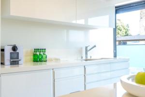 a white kitchen with a sink and a window at Moledo Front Beach by Portugal Active in Viana do Castelo