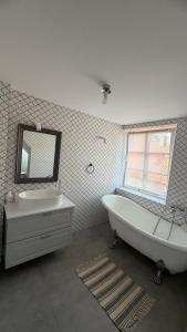 a bathroom with a tub and a sink and a mirror at Lotmiškio 1 in Neringa