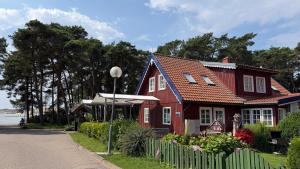 a red house with a fence next to a street at Lotmiškio 1 in Neringa