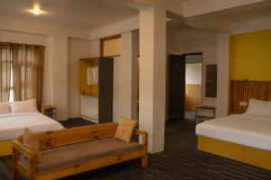 a hotel room with two beds and a bench at Sarai Stay in Kargil