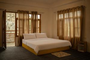 a bedroom with a bed and a large window at Sarai Stay in Kargil