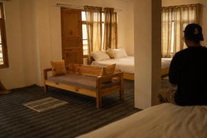 a man sitting in a room with two beds at Sarai Stay in Kargil +24 photos