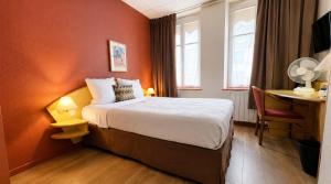 a hotel room with a bed and a desk and window at Logis-Hôtel des Oliviers in Thionville