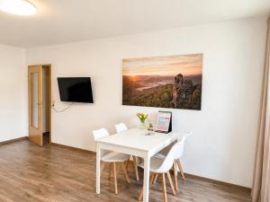 a white dining room with a white table and chairs at Urlaubsmagie Ferienwohnung Wiesengrün - direkt am Wanderweg - für 6P - W6 in Sebnitz