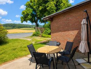 a patio with a table and chairs and an umbrella at Urlaubsmagie Ferienwohnung Wiesengrün - direkt am Wanderweg - für 6P - W6 in Sebnitz