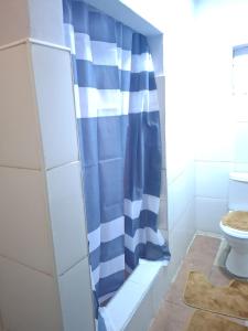 a bathroom with a blue and white shower curtain at Elimisam cabin in Kitwe +7 photos
