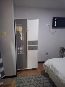 a bedroom with a white cabinet and a bed at Elimisam cabin in Kitwe