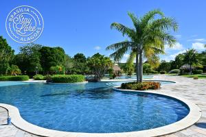 a swimming pool at a resort with a palm tree at Studio Iloa Vista Piscina 004V in Barra de São Miguel