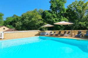 a swimming pool with chairs and umbrellas at Gîtes du Bois de Bontemps in Sarlat-la-Canéda